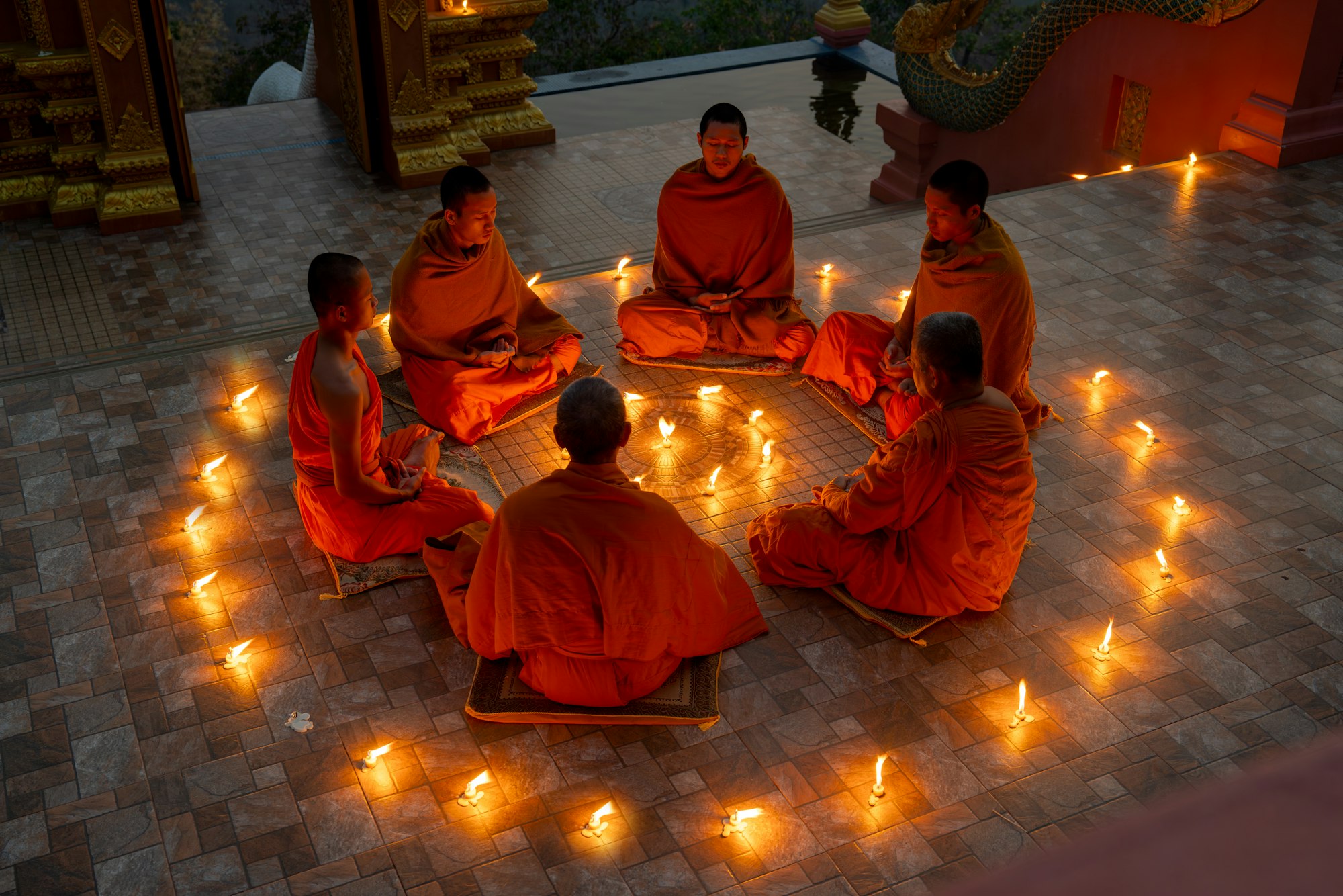 Close up group of young and senior monk sit in a circle with several lighting candle surround